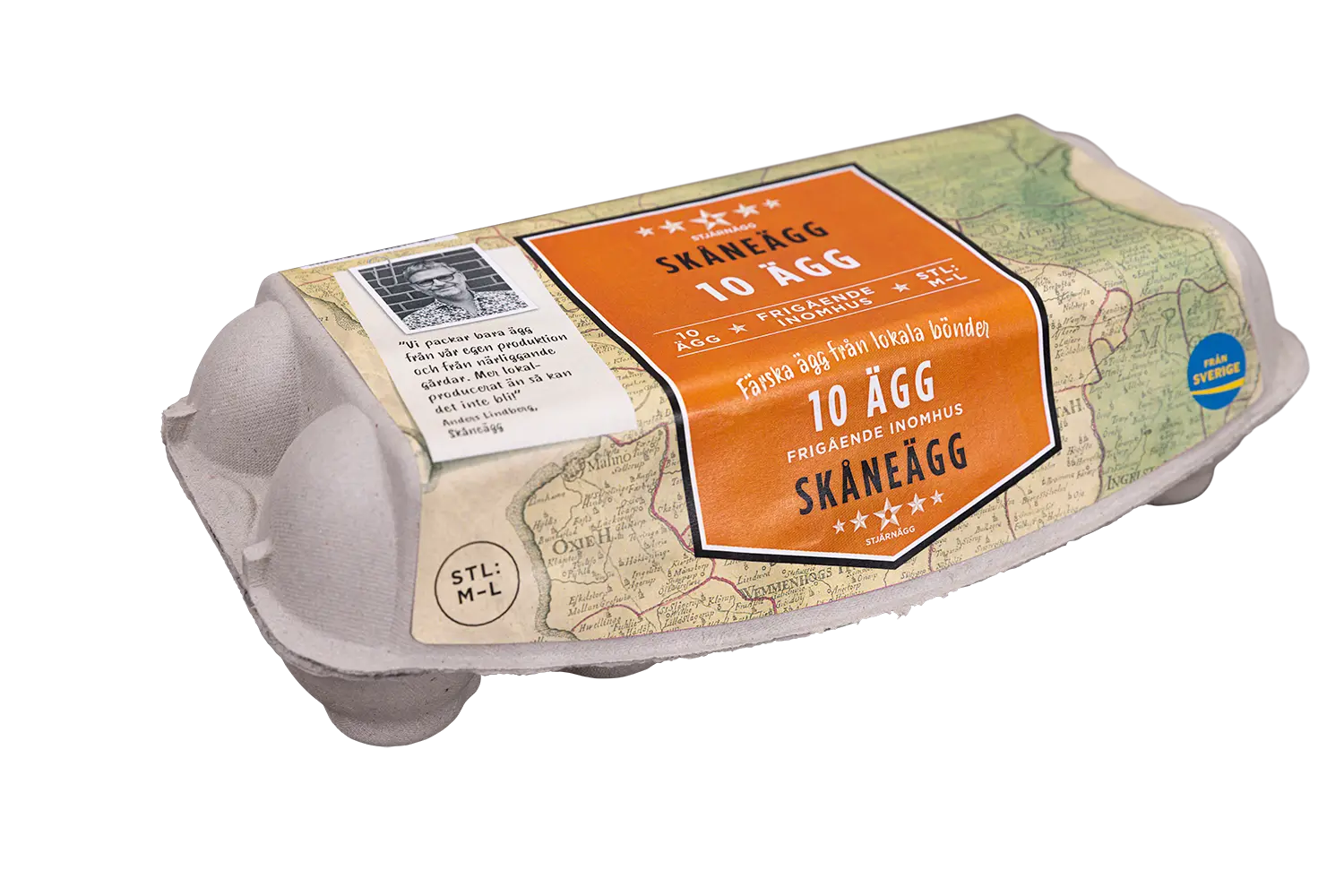 En kartong med 10 Skåneägg med en orange etikett med kartmotiv, text på svenska och ett litet svartvitt foto av en bonde på sidan. Kartongen är tillverkad av grå kartong.