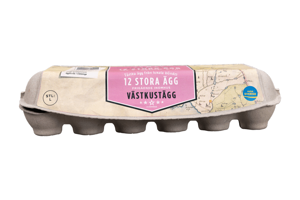 En kartong med 12 stora ägg med en rosa och beige etikett med texten "12 Stora Ägg" och "Västkustägg". Etiketten har en vintage kartdesign och en blå stämpel som anger att äggen är från Sverige.