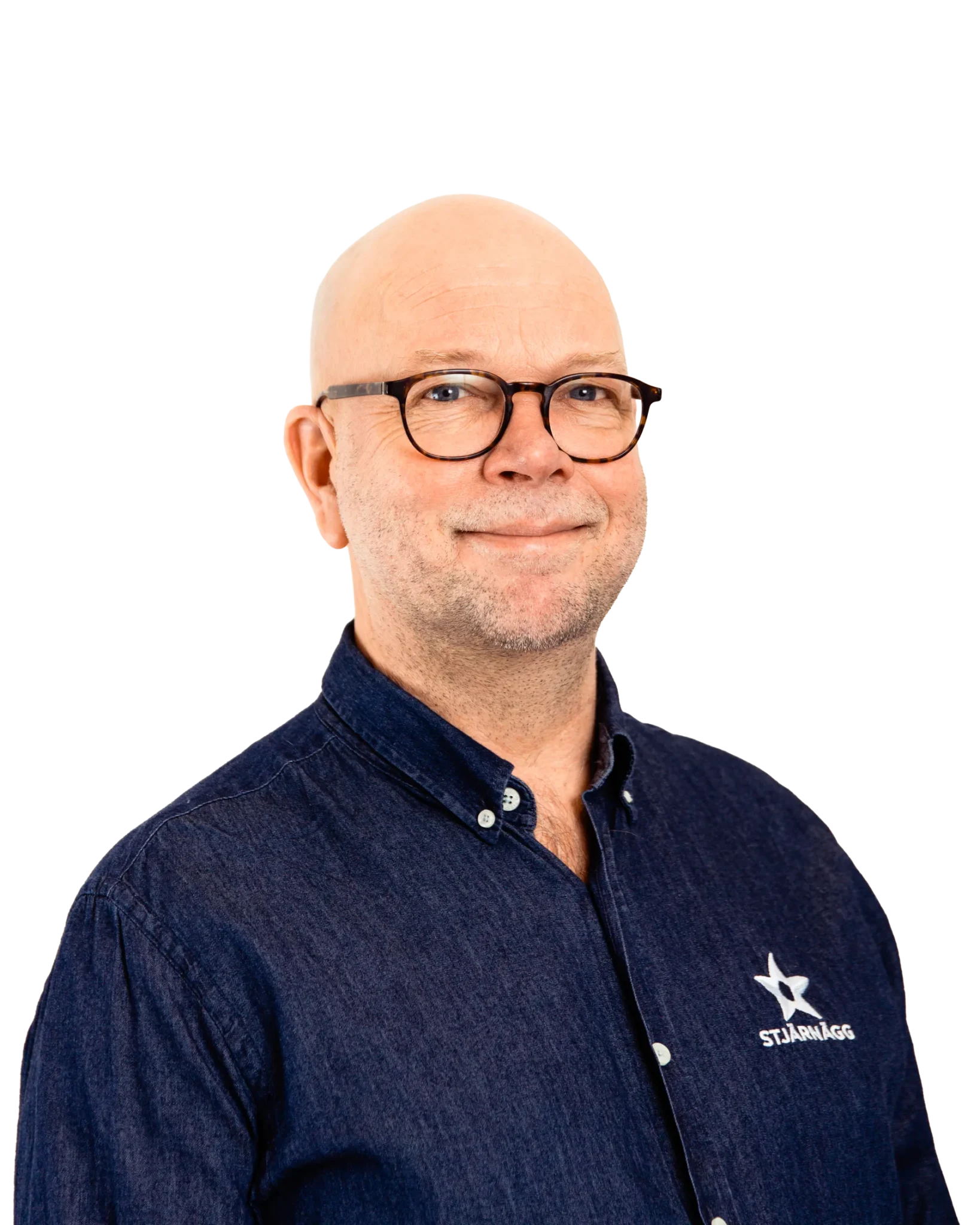 En medelålders man med glasögon, flintskallig hjässa och ett litet leende, klädd i mörkblå skjorta med vita stjärnor och STJÄRNÄGG logotyp, poserar mot en vit bakgrund.